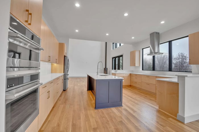 Custom LEED Gold-Certified Smart Home kitchen featuring light wood flooring and cabinetry and stainless steel appliances