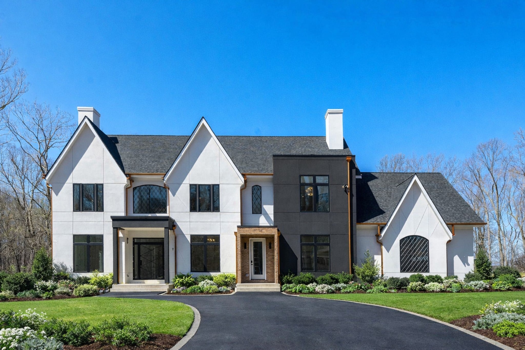 driveway view of modern tudor custom home in dmv area with copper gutters and downspouts original size