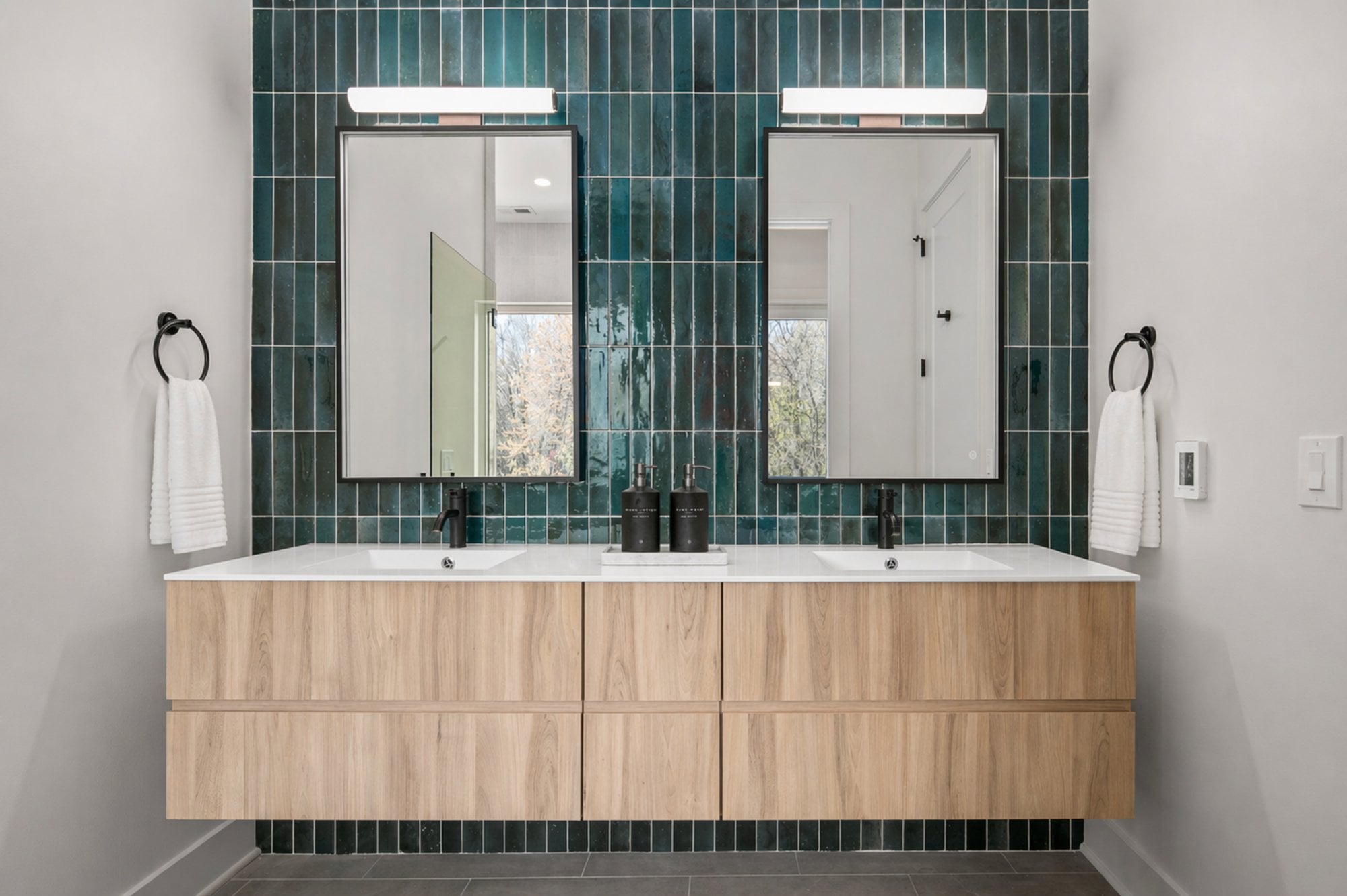 boyds modern bath by august homes double vanity bathroom with green tile wall floating wood cabinets and backlit mirrors